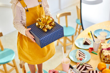 top view on cropped girl holding gift box in hands, next to decorated table