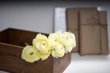 Bouquet of yellow ranunculus in a wooden box with wrapped gifts