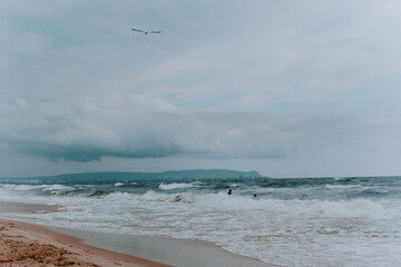a few people are swimming in the sea in a storm. stormy skies and huge waves of the sea. sandy...