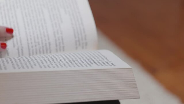 Une femme avec du vernis &agrave; ongle rouge qui lis un livre
