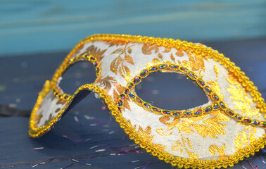 Mardi gras mask and beads on a wooden background. Madi Gras carnival accessories, confetti,...