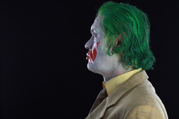  Portrait of a smiling man with clown makeup and green hair.