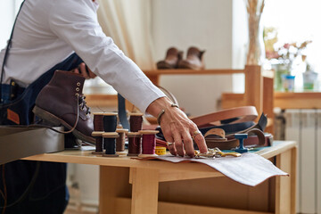 working process of the leather things in the leather workshop, craftsman concentrated on making belt, using tools.