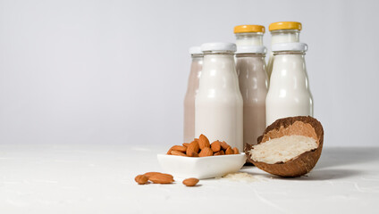 a variety of lactose-free milk from nuts and grains in glass bottles. light vegan concept with a milk drink made from hazelnuts, oats, coconut, almonds, walnuts, rice