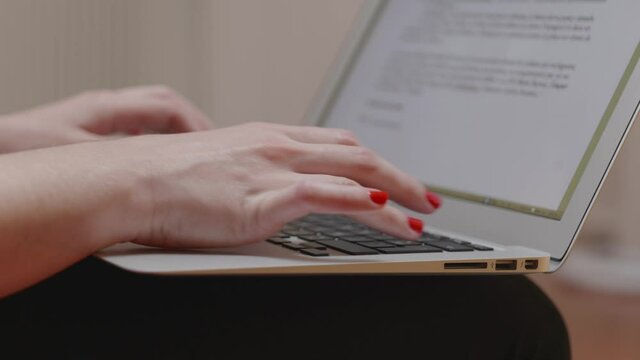 Une femme avec du vernis &agrave; ongle rouge qui tape sur un clavier d'ordinateur