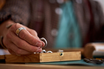 close-up photo of male jeweler hands holding ring, pulls out of the case, focus on hands with jewelry