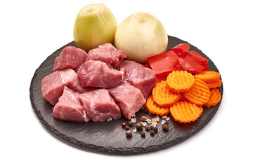 Raw pork pieces on a stone plate, ingredients for goulash, isolated on white background