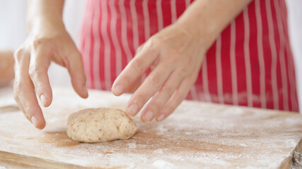 Whole wheat bread from homemade whole grain dough made by woman with red apron. Healthy pastry with many grains.