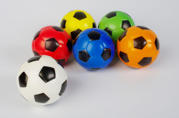 Multi-colored toy soccer balls on a light background.