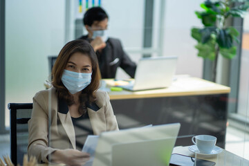 Asian business woman with colleague male in new normal social distancing office with colleague