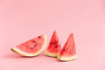 Three small pieces of watermelon on a pink background