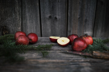 Homemade fresh apples on a wooden background. Chopped apple, knife and spruce twigs.