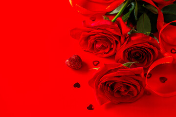 Red roses and decor in the shape of a heart on a red background. Copy space.