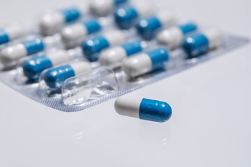 The medicine is in the form of blue and white capsules.