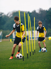 Young Football Players Running Slalom and Dribbling With Balls Between Training Poles. Soccer...