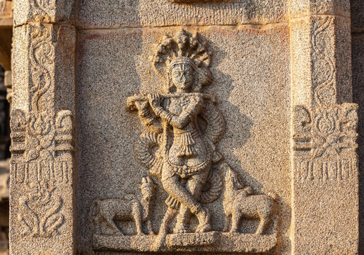 Hampi, Karnataka, India - November 4, 2013: Hazara Rama Temple. Closeup of beige stone sculptures of flute player with Manasa snakes around and smaller animals.