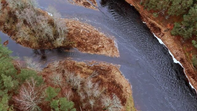 Red sandstone cliffs in the banks of river Salaca during late autumn time, Latvia. Real time drone footage