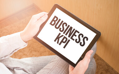Man using digital tablet, close-up, coffee and keyboard on the background. Text BUSINESS KPI