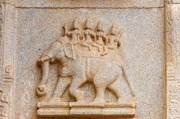 Hampi, Karnataka, India - November 4, 2013: Hazara Rama Temple. Closeup of beige stone sculptures of 2 women and 2 men on elephant.