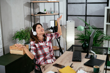 Portrait of businesswoman in office. Beautiful woman listening music at work
