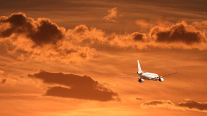 Fototapeta na wymiar Zoom photo of modern passenger airplane flying towards sunset with cloudy sky and beautiful golden colors