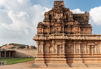 Hampi, Karnataka, India - November 4, 2013: Hazara Rama Temple. Side view on warm brown inner sanctum with shorter viamanam under sunset light and blue cloudscape. Plenty of sculptures.