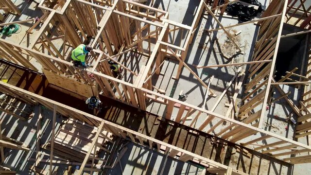 Aerial view of a new building being framed by carpenters. Worker builder working on building structure on construction site.