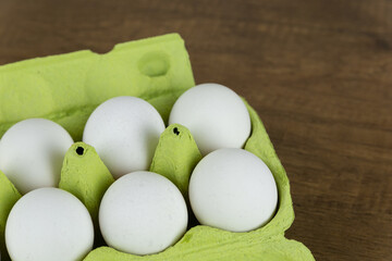 Opened egg box with ten eggs inside, on a wooden background. Fresh organic chicken eggs in carton or egg container. Fresh chicken eggs. View from above. Natural organic egg.