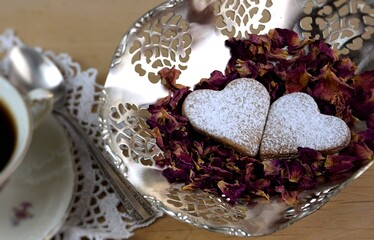 Dwa ciasteczka serduszka w płatkach róż, obok kawa, romantyczny walentynkowy obraz, retro