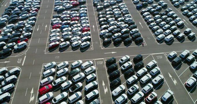 A large number of cars parked in angled parking spaces. Wonderful view with drone above white roofs of cars in a parking lot - aerial view with a drone 4K