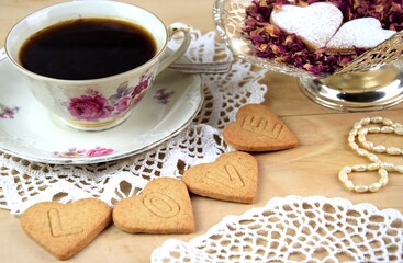 LOVE ciasteczka serca z napisem na drewnianym tle, filiżanka z kawą, płatki róż,Walentynkowe...