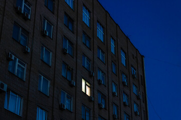 Obraz premium One luminous window in a multi-storey building at night.
