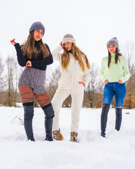 Winter lifestyle, three caucasian girlfriends with winter outfit and wool hats enjoying the snow, holidays in nature