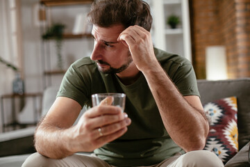 Depression man drinking alcohol at home. Lonely man is addicted of alcohol.