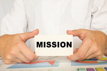 a man in the office holds a card with text MISSION . business concept