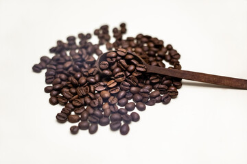 Coffee beans in wooden spoon. Arranged on a white background.