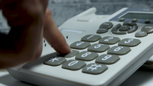 Video how to dial a phone number on a wired phone. Close shot.