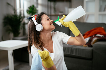 Young attractive woman cleaning home. Happy beautiful woman listetning the music, enjoying in cleaning..