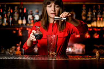view of glass into which drink from jigger is poured by bartender
