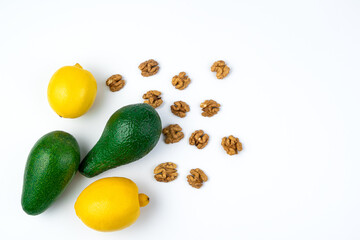Avocados, lemons and nuts on a white background. Top view with space to copy. The concept of healthy eating.