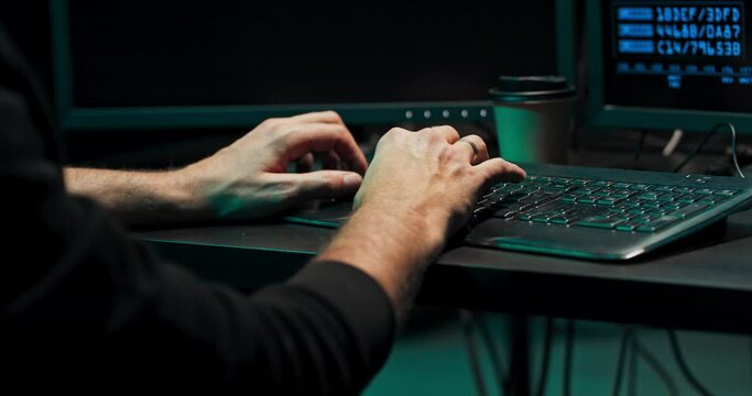 A computer programmer or hacker prints a code on a computer keyboard to break into a secret organization system.