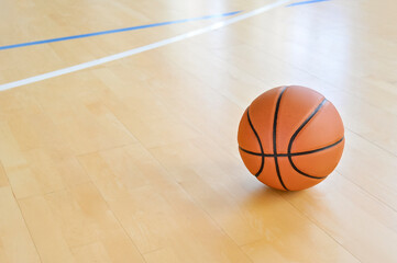 A basketball on the wooden floor as background. Team sport concept