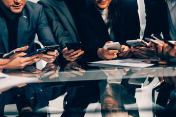 close up . employees with smartphones sitting at the Desk