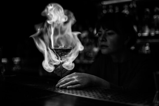 amazing view on wine glass on bar counter which female bartender sets in fire