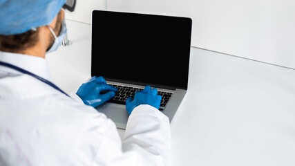 close up. doctor in protective gloves typing on a laptop .