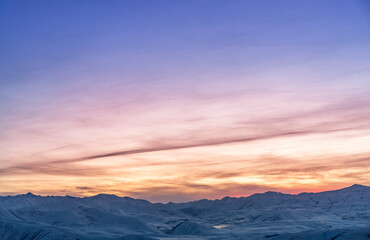 Beautiful winter landscape. The mountains peaks snow-covered on the sunset. Dramatic sky.