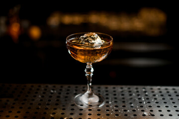 transparent wine glass of alcoholic drink with ice cube stands on the bar counter