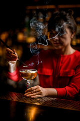 great view of bar counter with glass and woman bartender decorates it with smoldering plant