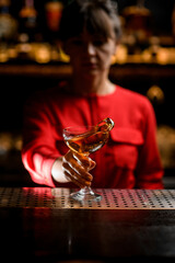 hand of woman bartender holds the leg of glass with drink and splashes it