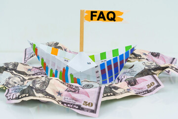 A paper boat from a business graph floats on a sea of money. The text is written on the flag - FAQ